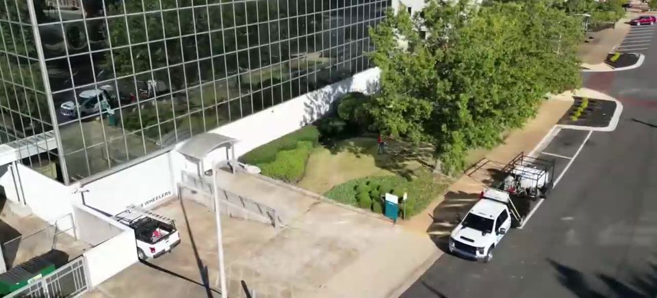 Aerial view of a glass office building with the Dirt and Grime truck and trailer parked below.