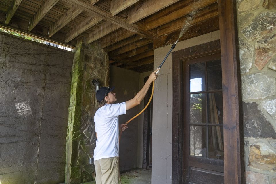 A Dirt and Grime crew member soft washing an exterior wall.